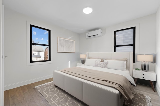 bedroom with hardwood / wood-style floors and an AC wall unit