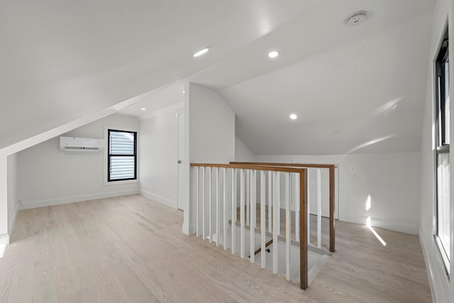 bonus room with a wall mounted air conditioner, vaulted ceiling, and light wood-type flooring