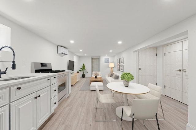 dining room featuring a wall unit AC, sink, and light wood-type flooring