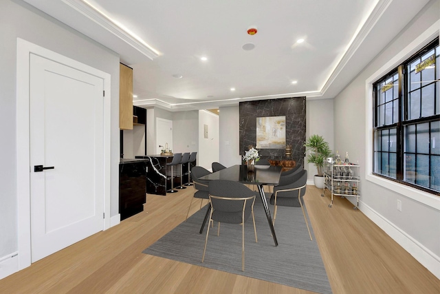 dining room featuring a healthy amount of sunlight, a tray ceiling, and light hardwood / wood-style flooring