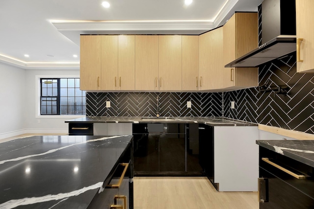 kitchen with light brown cabinets, light hardwood / wood-style floors, wall chimney range hood, and ornamental molding