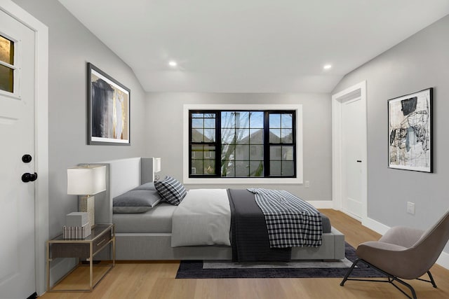 bedroom with light hardwood / wood-style floors and lofted ceiling