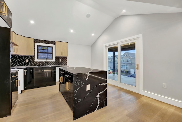 kitchen with tasteful backsplash, vaulted ceiling, light brown cabinets, light hardwood / wood-style flooring, and a kitchen island