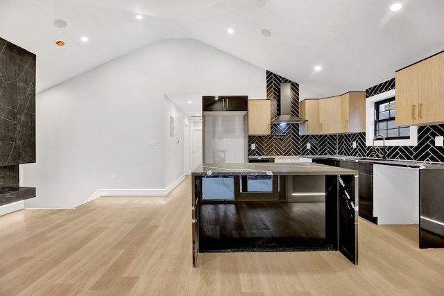 kitchen with lofted ceiling, a kitchen island, light wood-type flooring, and wall chimney range hood