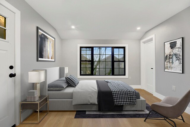 bedroom with lofted ceiling and light wood-type flooring