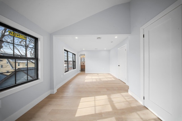 spare room with vaulted ceiling and light hardwood / wood-style flooring