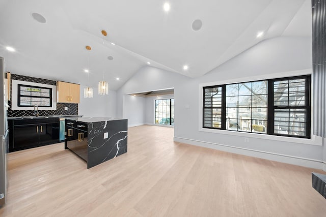 kitchen featuring decorative light fixtures, tasteful backsplash, a center island, light hardwood / wood-style floors, and light brown cabinets