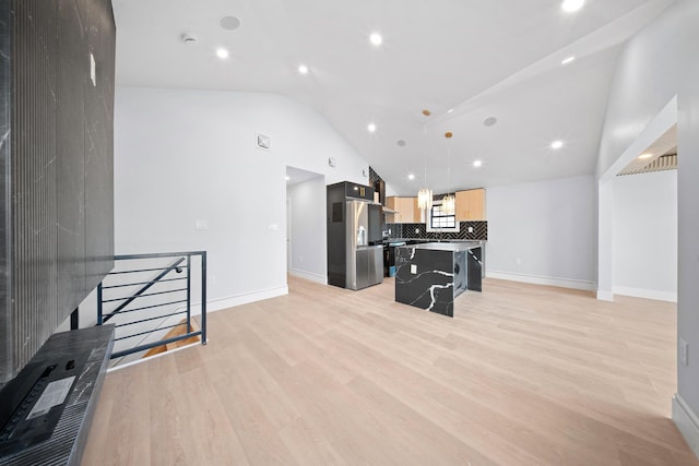 kitchen with a kitchen island, decorative light fixtures, stainless steel fridge, a kitchen bar, and light brown cabinets