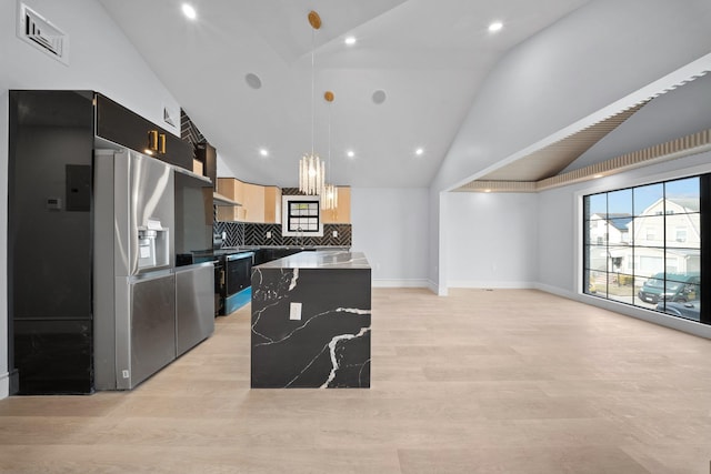 kitchen featuring decorative light fixtures, a center island, vaulted ceiling, dark stone countertops, and light wood-type flooring