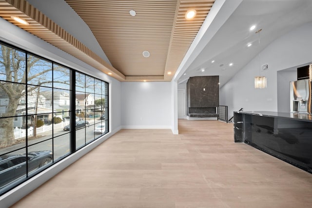 corridor featuring lofted ceiling, a tray ceiling, and light hardwood / wood-style flooring