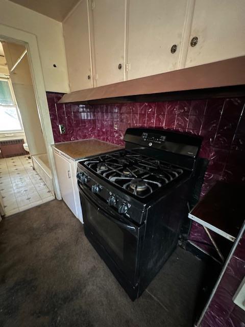 kitchen with white cabinets, black gas stove, and backsplash