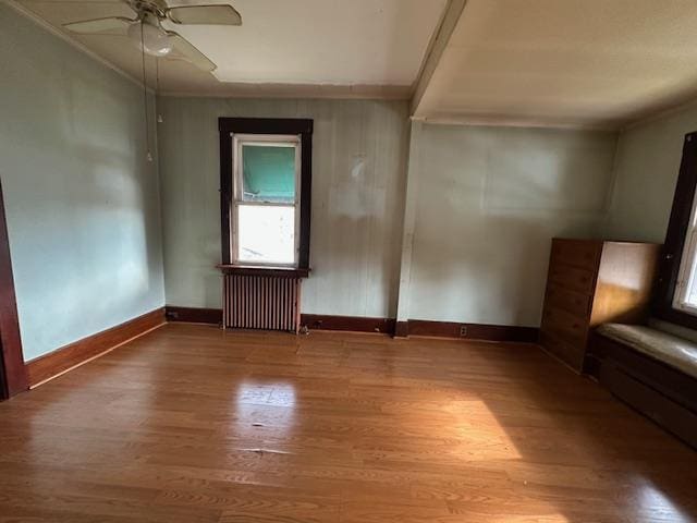 unfurnished room with ceiling fan, crown molding, radiator heating unit, and hardwood / wood-style flooring