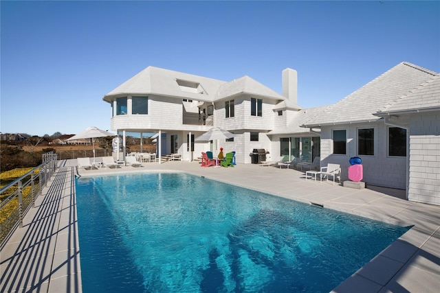 rear view of property featuring a patio and a fenced in pool