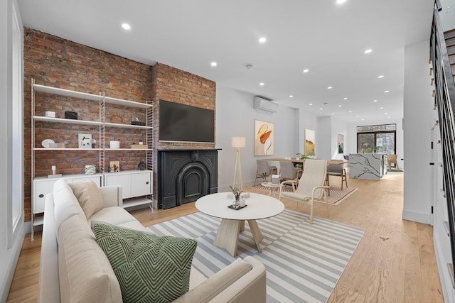 living room featuring light wood-type flooring, an AC wall unit, and brick wall