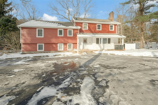 snow covered back of property featuring a porch