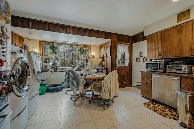 dining space with baseboard heating, washing machine and clothes dryer, light tile patterned floors, and wood walls