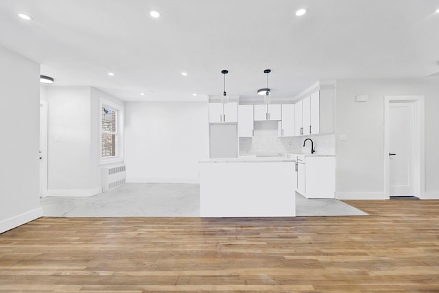 kitchen featuring tasteful backsplash, white cabinetry, light hardwood / wood-style flooring, and hanging light fixtures