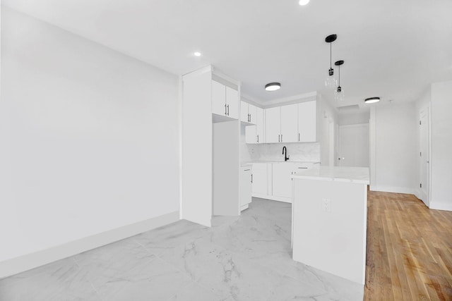 kitchen featuring backsplash, sink, decorative light fixtures, a kitchen island, and white cabinetry