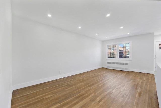 unfurnished living room featuring radiator heating unit and hardwood / wood-style flooring