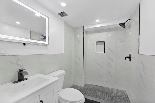 bathroom with vanity, toilet, and tiled shower