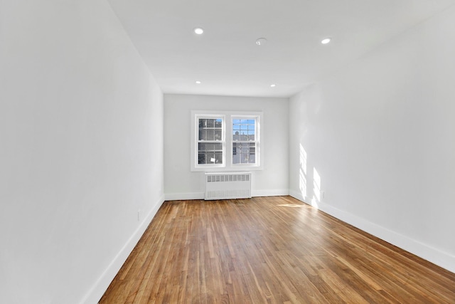 unfurnished room featuring hardwood / wood-style flooring and radiator