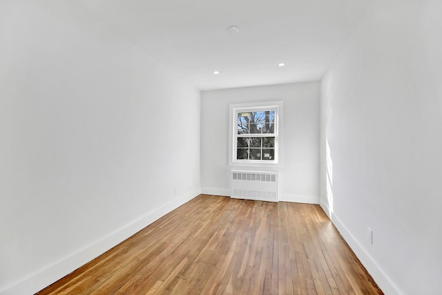 empty room with light wood-type flooring and radiator heating unit