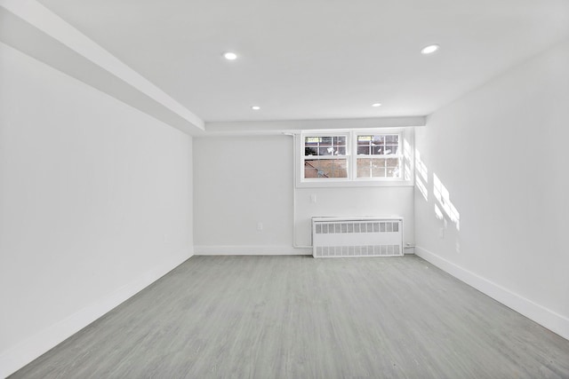 empty room with radiator heating unit and light hardwood / wood-style flooring