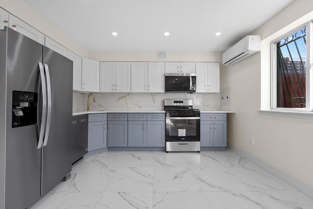 kitchen featuring a wall mounted AC, white cabinetry, gray cabinetry, and stainless steel appliances