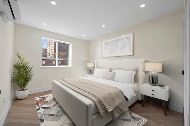 bedroom with a wall mounted air conditioner and light wood-type flooring