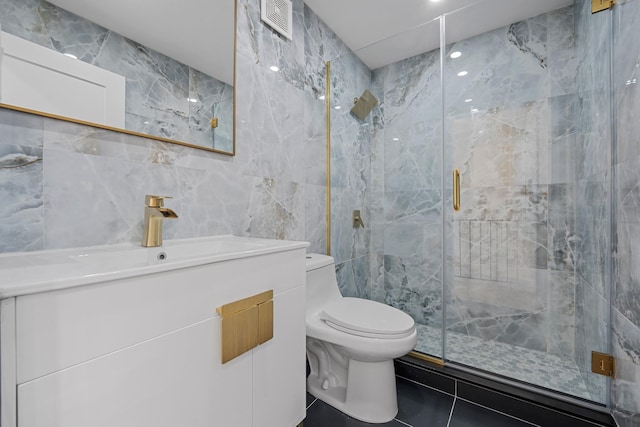 bathroom with vanity, toilet, a shower with shower door, and tile walls