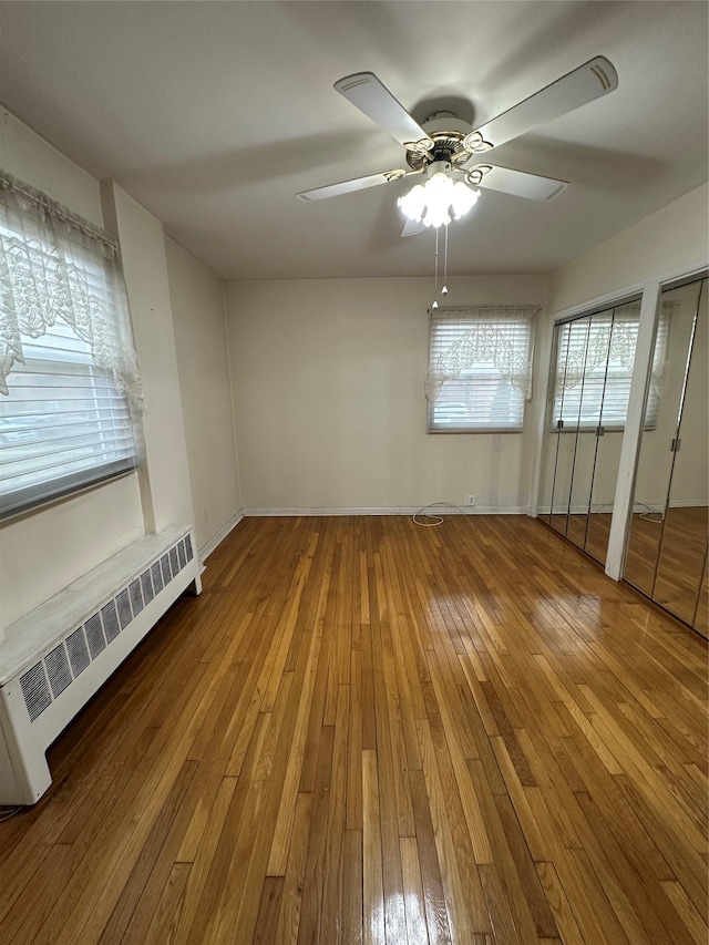 unfurnished room with ceiling fan, wood-type flooring, radiator heating unit, and a baseboard heating unit