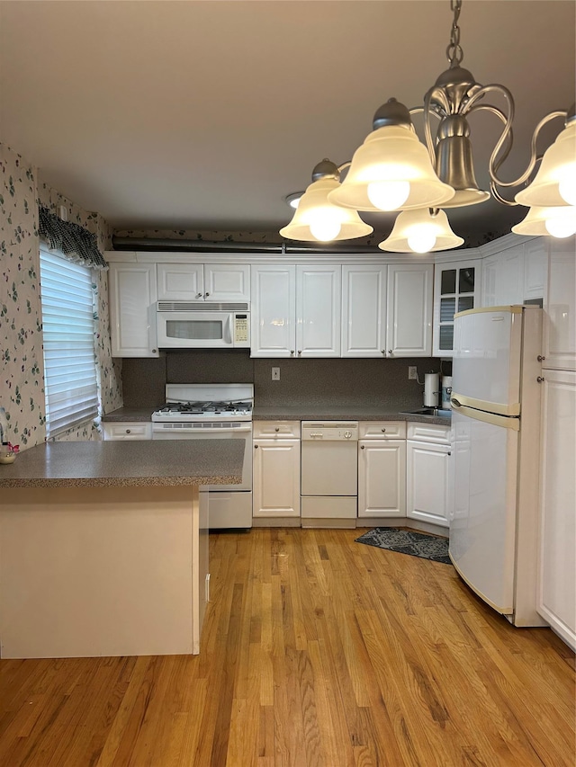 kitchen with white cabinetry, light hardwood / wood-style floors, decorative light fixtures, and white appliances