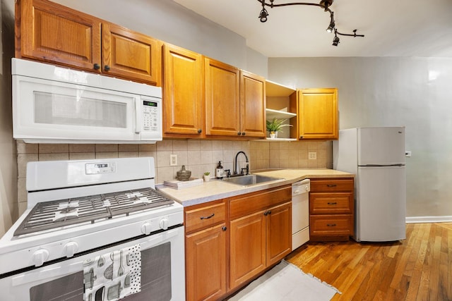 kitchen featuring decorative backsplash, light wood-type flooring, white appliances, and sink