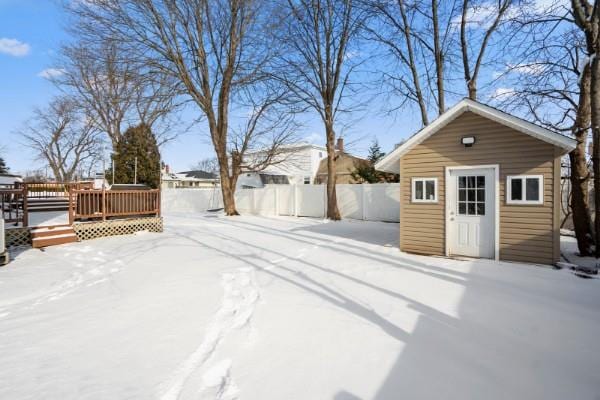 yard covered in snow featuring a wooden deck and an outdoor structure