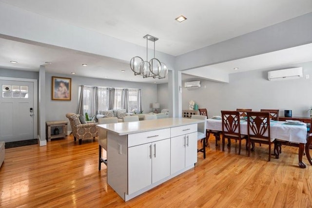 kitchen with pendant lighting, a wall mounted air conditioner, light hardwood / wood-style floors, and white cabinets