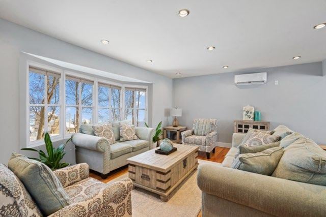 living room featuring a wall mounted air conditioner and light hardwood / wood-style flooring