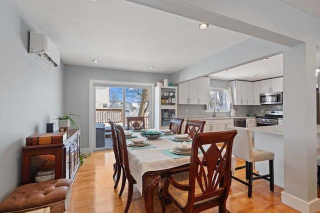 dining area with a wall mounted air conditioner and light hardwood / wood-style flooring