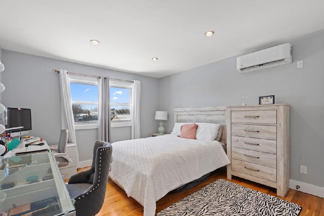 bedroom with a wall mounted AC and light hardwood / wood-style floors