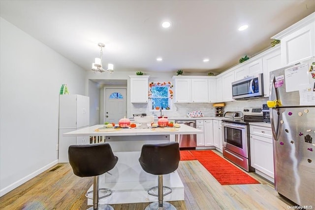 kitchen featuring hanging light fixtures, an inviting chandelier, tasteful backsplash, white cabinets, and appliances with stainless steel finishes