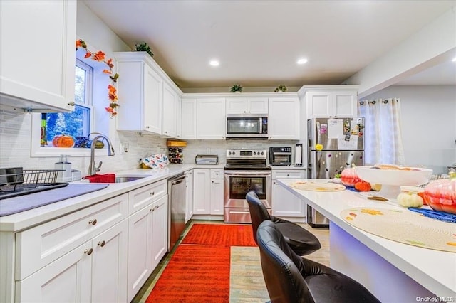 kitchen featuring backsplash, stainless steel appliances, white cabinetry, and sink