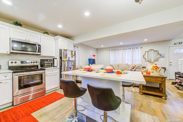 kitchen featuring a kitchen breakfast bar, white cabinetry, and stainless steel appliances