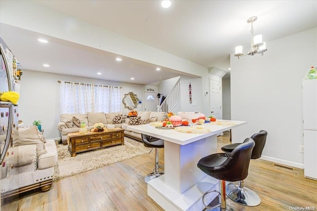 kitchen featuring a kitchen breakfast bar, an inviting chandelier, hanging light fixtures, and light wood-type flooring