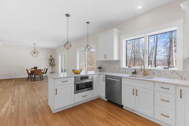 kitchen featuring stainless steel appliances, white cabinets, pendant lighting, and sink