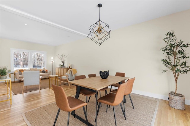 dining area with a notable chandelier, light hardwood / wood-style floors, and beam ceiling