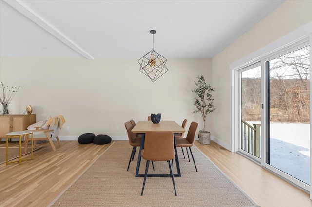 dining space with light hardwood / wood-style floors and beam ceiling