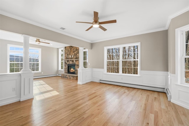 unfurnished living room with light hardwood / wood-style floors, a stone fireplace, baseboard heating, and crown molding