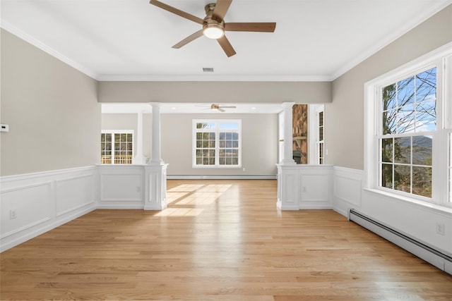 spare room with ceiling fan, ornamental molding, baseboard heating, light hardwood / wood-style floors, and decorative columns