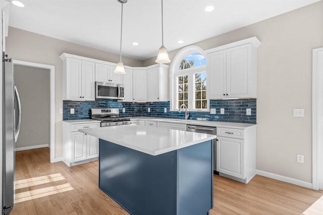 kitchen with a center island, stainless steel appliances, white cabinetry, and hanging light fixtures