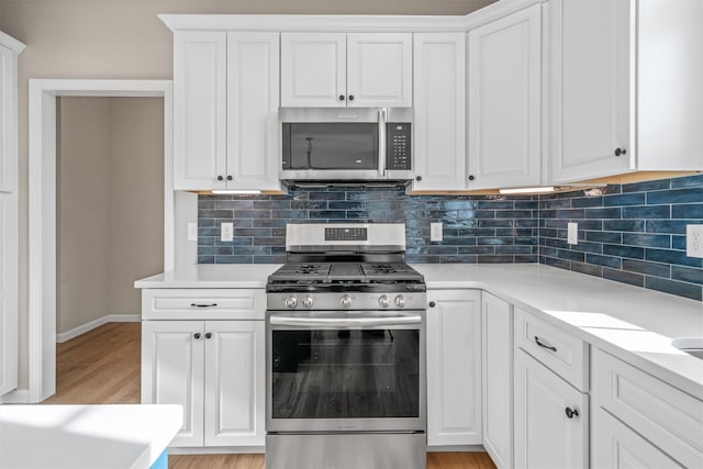 kitchen featuring tasteful backsplash, white cabinets, stainless steel appliances, and light hardwood / wood-style floors