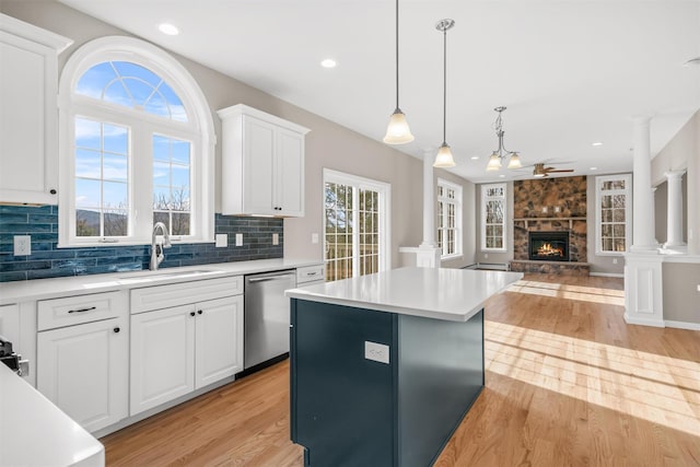 kitchen featuring dishwasher, sink, ceiling fan, a fireplace, and white cabinetry